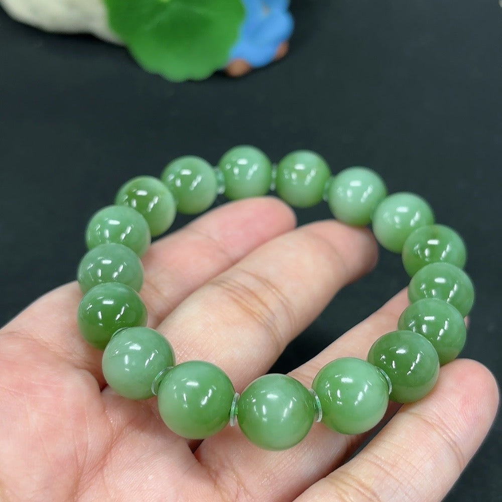 Green Hetian Jade bracelet by HKHQ featuring smooth, polished jade beads strung together on an elastic band.