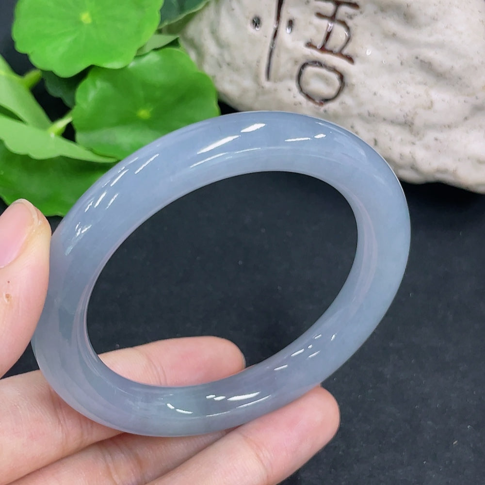 HKHQ jadeite round bangle showcasing smooth, polished green jade with a glossy finish on a neutral background.