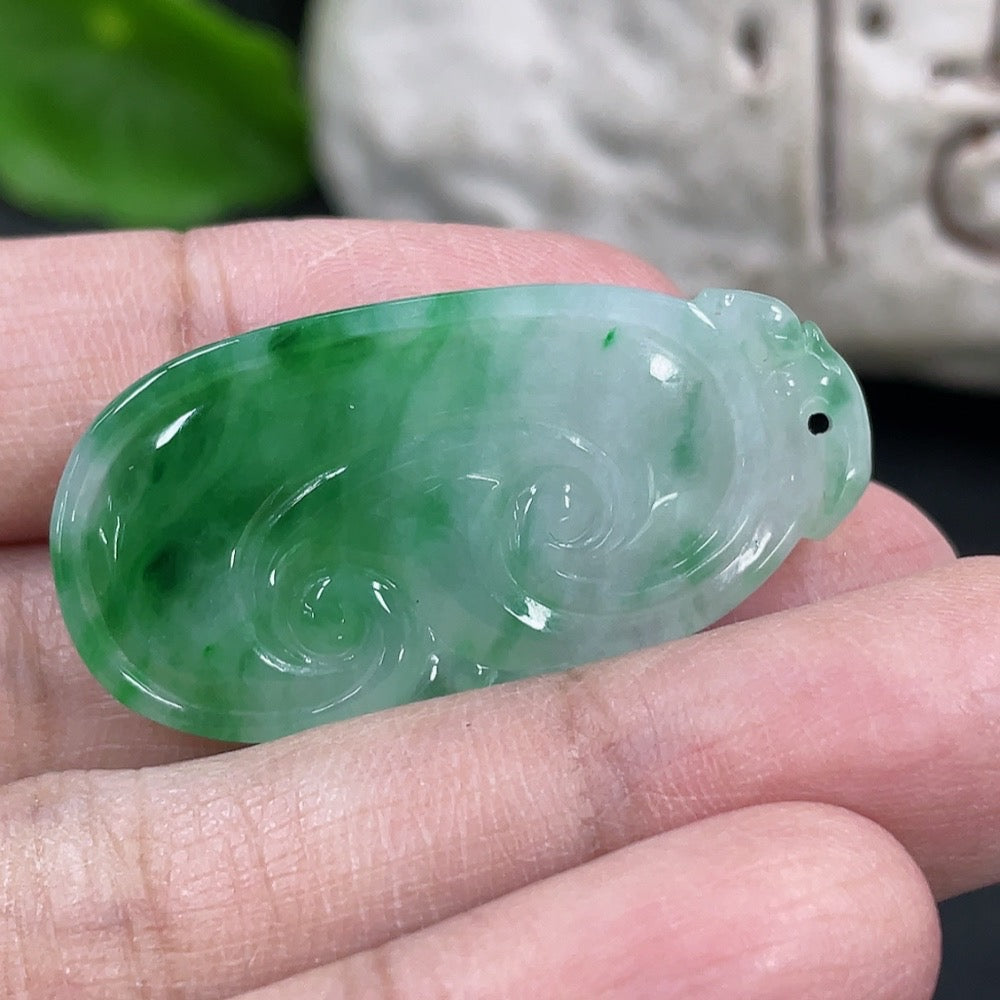 Jadeite Ruyi pendant necklace featuring a polished green jadeite stone with carved details, hanging on a silk cord.