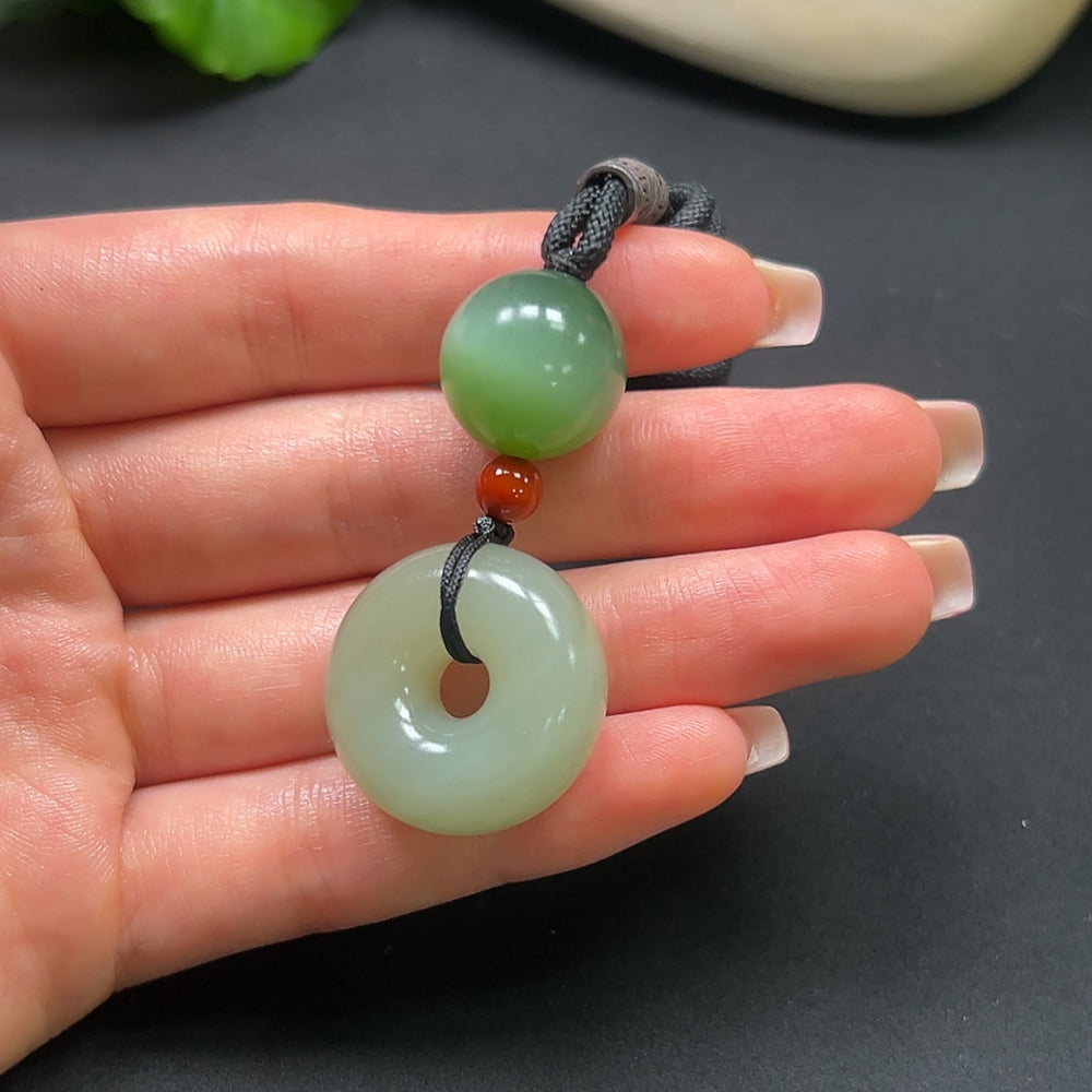 Hetian jade peace knot pendant with southern red accents, weighing 22.9g, shown with attached rope, by HKHQ.