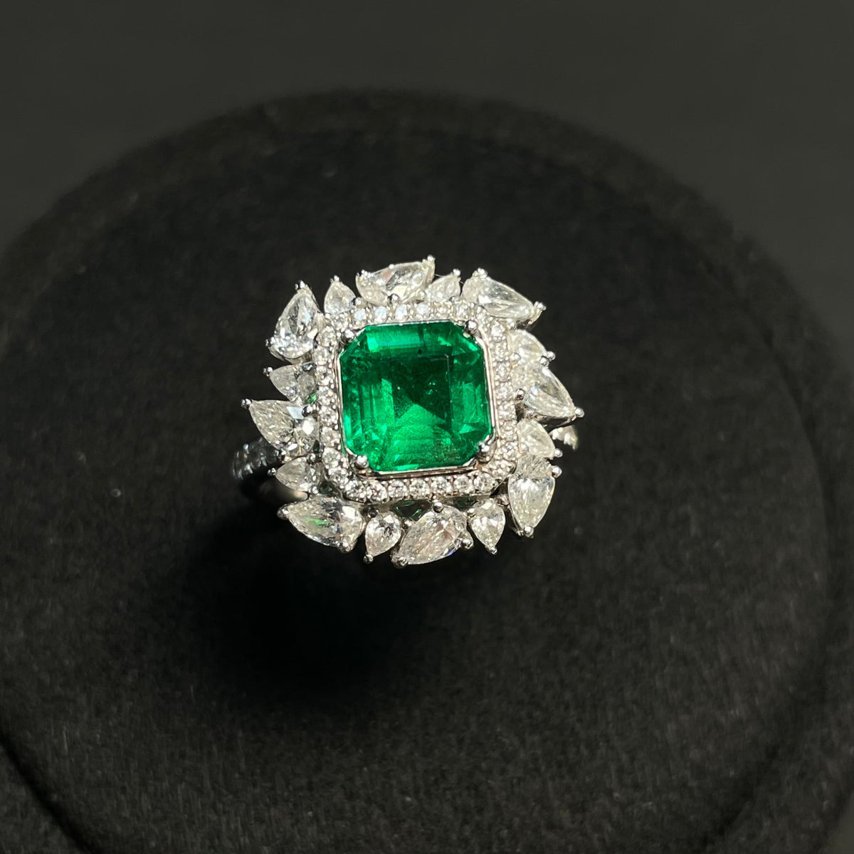 Emerald ring with diamond accents in 18K gold, featuring clarity-enhanced emerald and intricate gold band design.