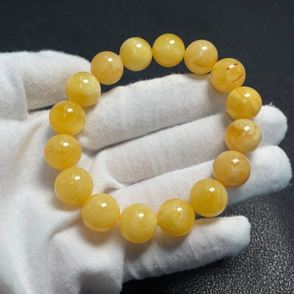 Amber beeswax bracelet by HUILIU HQ featuring visible repair marks, approximately 12.6mm in size, showcasing natural amber beauty.