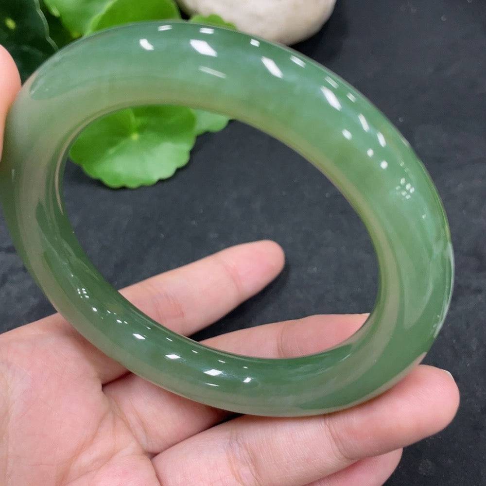 Green Hetian Jade round bangle with smooth surface, engraved with subtle natural patterns, showing a polished finish.