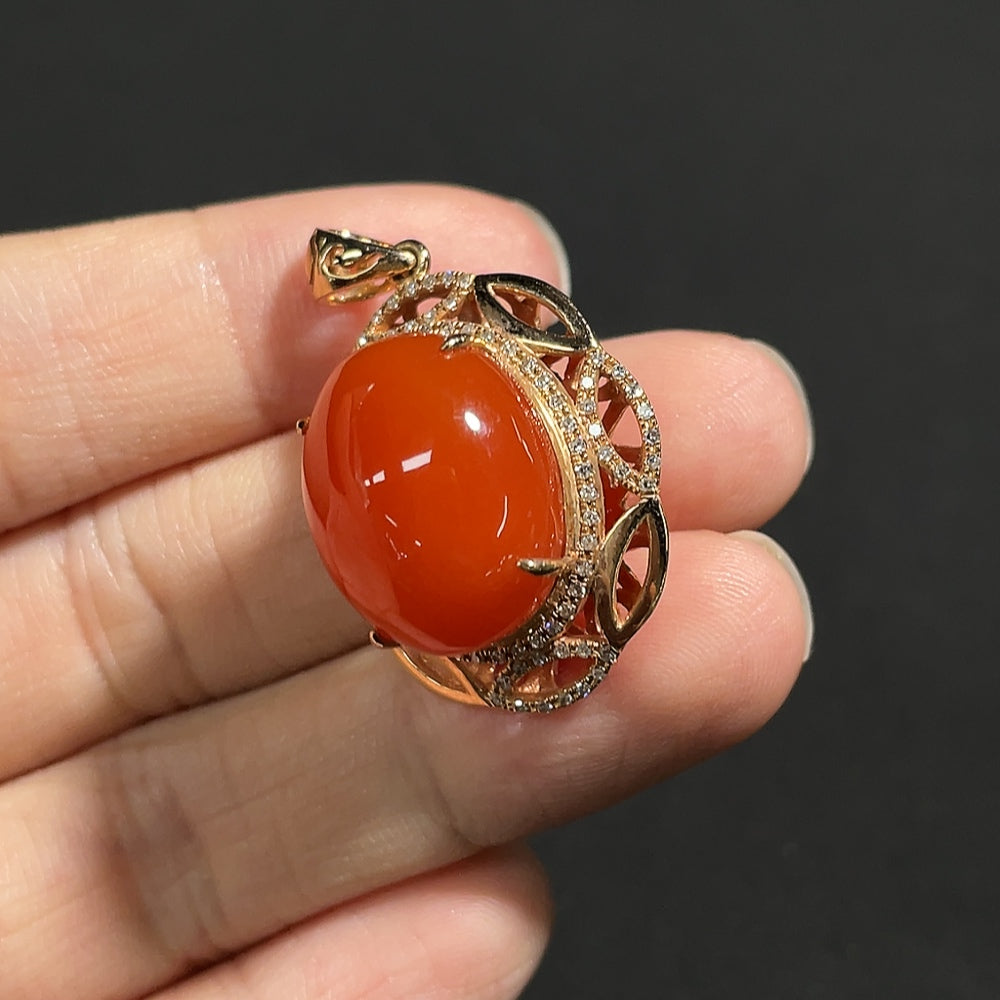 Red agate gemstone pendant with diamond accents, 18K gold setting, visible organic matter, weighing approximately 5.9g.