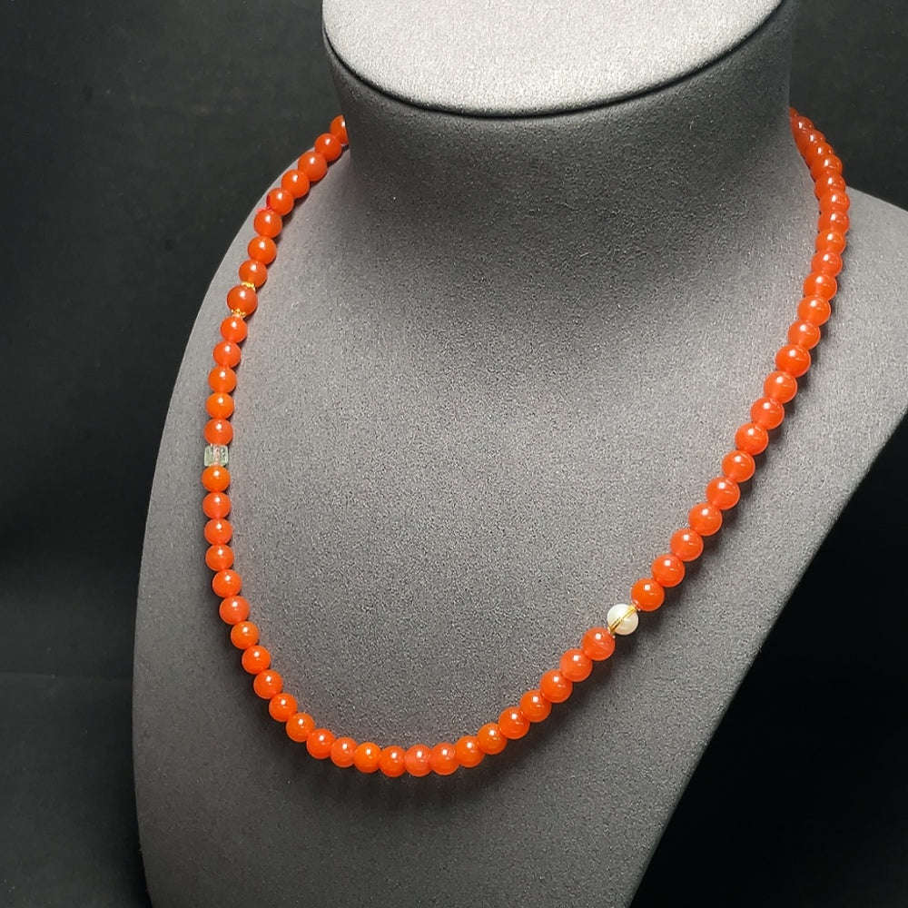 Red agate bead strand necklace with 18K gold accents, featuring tourmaline and pearl details, displayed against a neutral background.