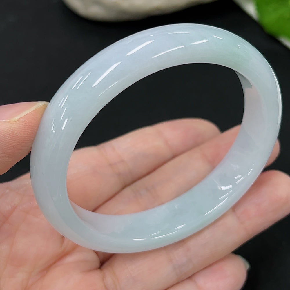 HKHQ Jadeite oval bangle in size 54.6 with a 44.9g weight, showcasing smooth, polished green jadeite jewelry on a neutral background.