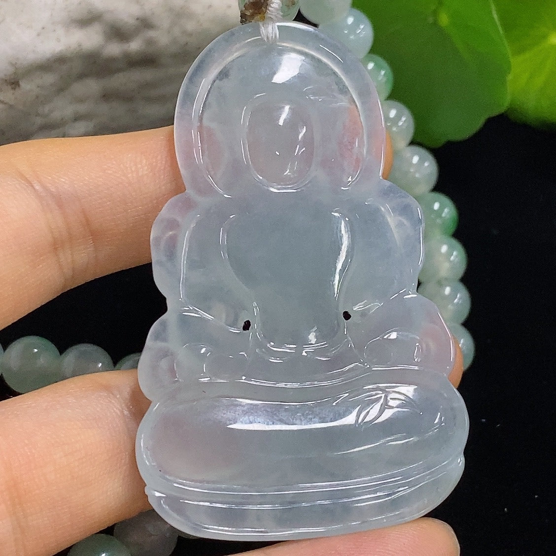 Jadeite Tara pendant crafted from green jade, featuring intricate carvings, hanging from a delicate silver chain.