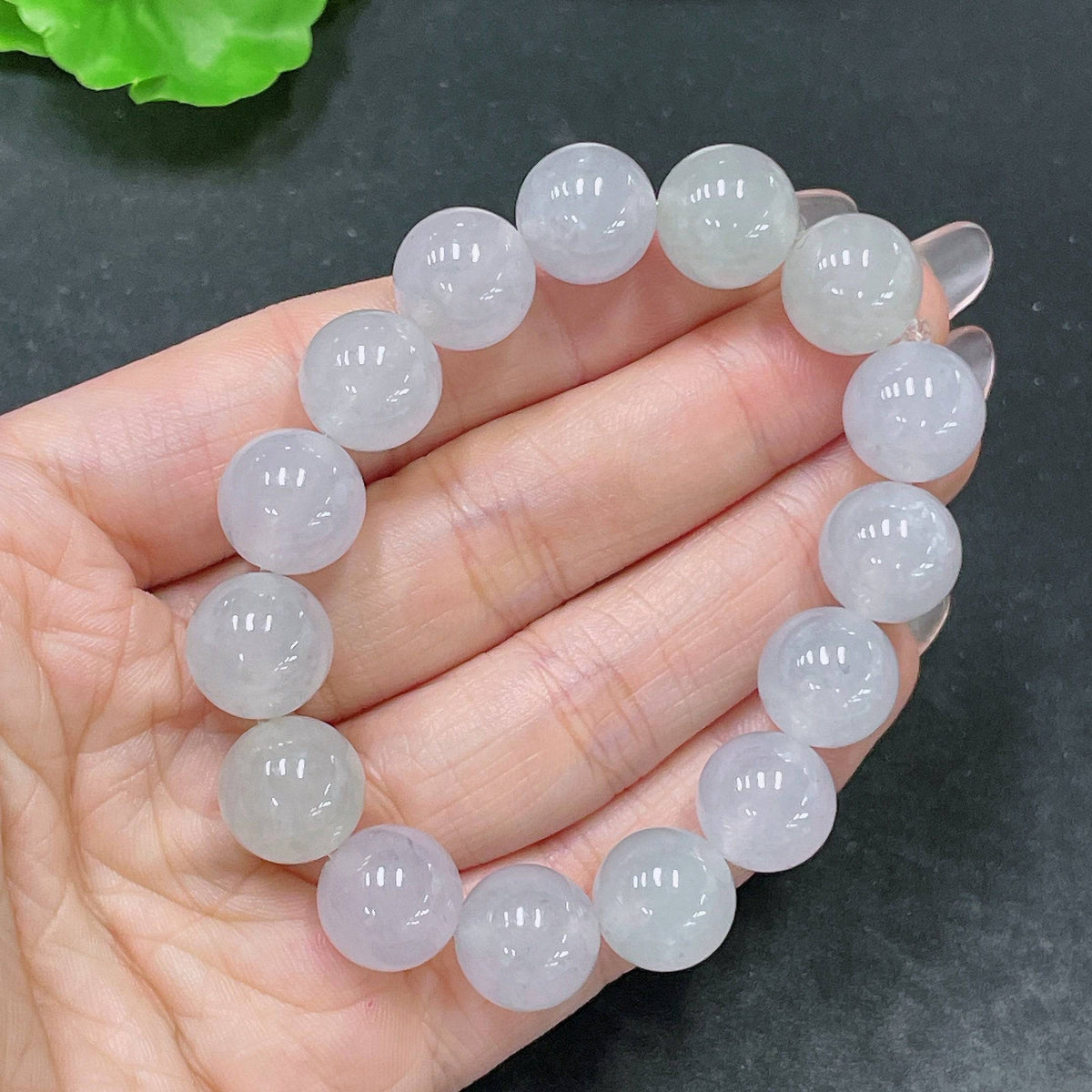 Huiliu Jadeite bracelet featuring round 12.3mm jade beads, certified by Huiliu, displayed in close-up with natural lighting.