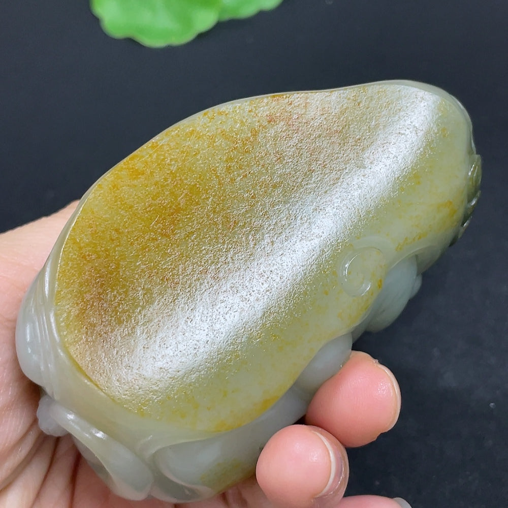 Hand holding a Hetian jade seed material hand piece from HKHQ, showcasing its smooth, polished jade surface and intricate craftsmanship.