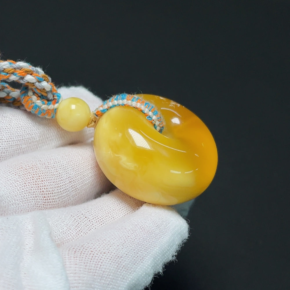 Amber beeswax pendant with cord, weighing approximately 20.21g, crafted by HKHQ, showcasing warm amber tones and natural texture.
