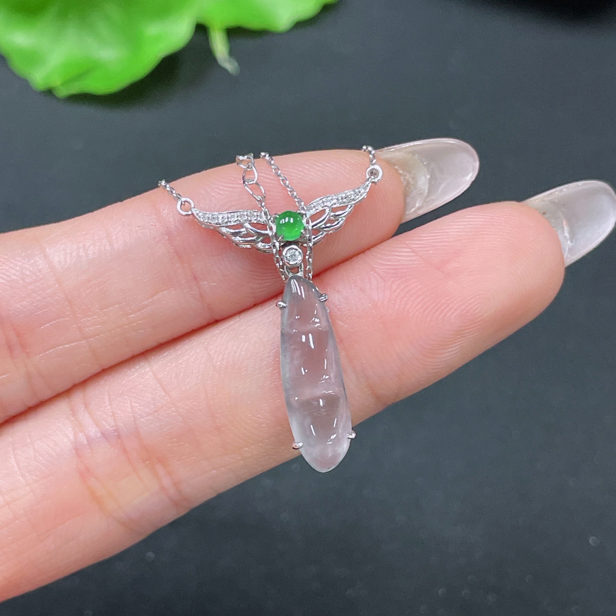 Jadeite bean pendant set in 18k gold with diamond accents, displayed on a chain, weighing approximately 2.74 grams.