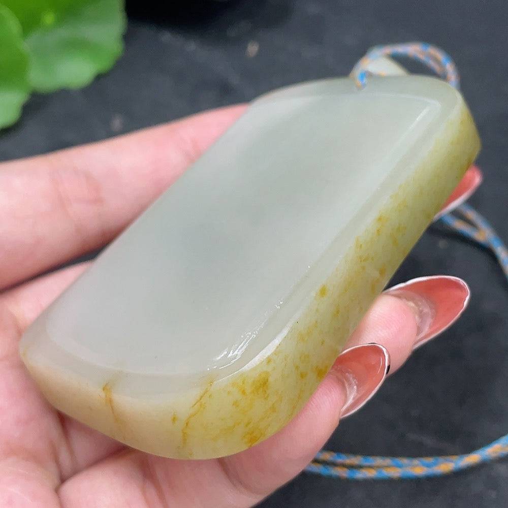 Huiliu certified Hetian jade seed pendant with plain design on string, natural skin color formation, showcasing smooth jade surface.