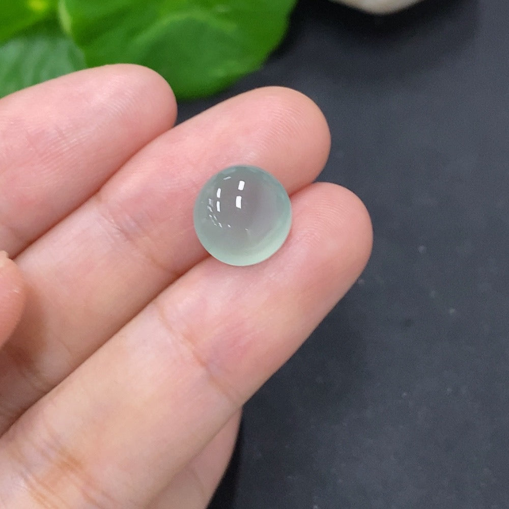 Jadeite cabochon jewelry piece from HKHQ, displaying a smooth, polished green gemstone with a glossy finish.