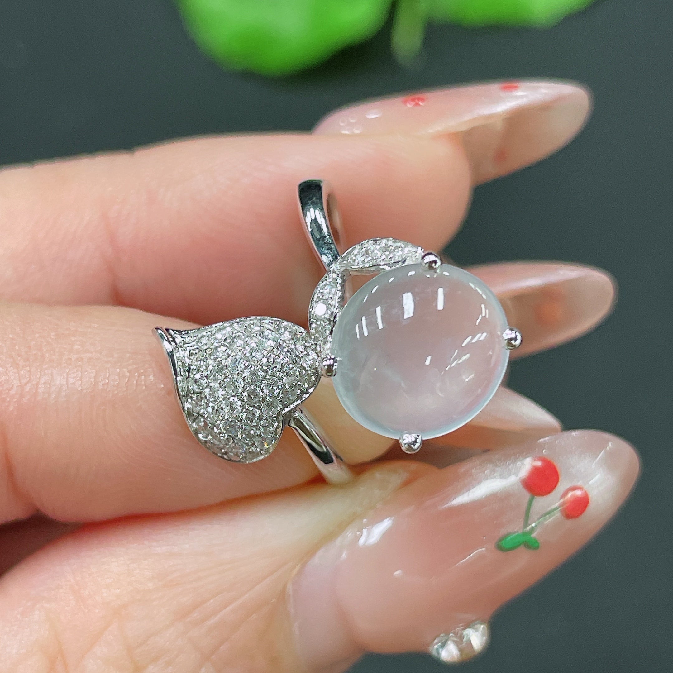 Jadeite cabochon ring with 18k gold band and diamond accents, size 12, worn on finger.