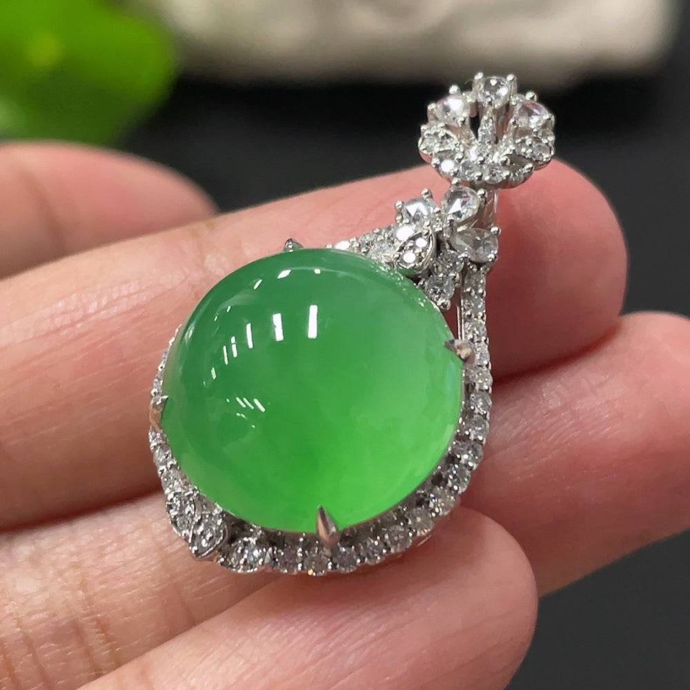 Jadeite cabochon pendant with 18K gold setting and diamond accents, featuring a polished jade gemstone in a jewelry display.