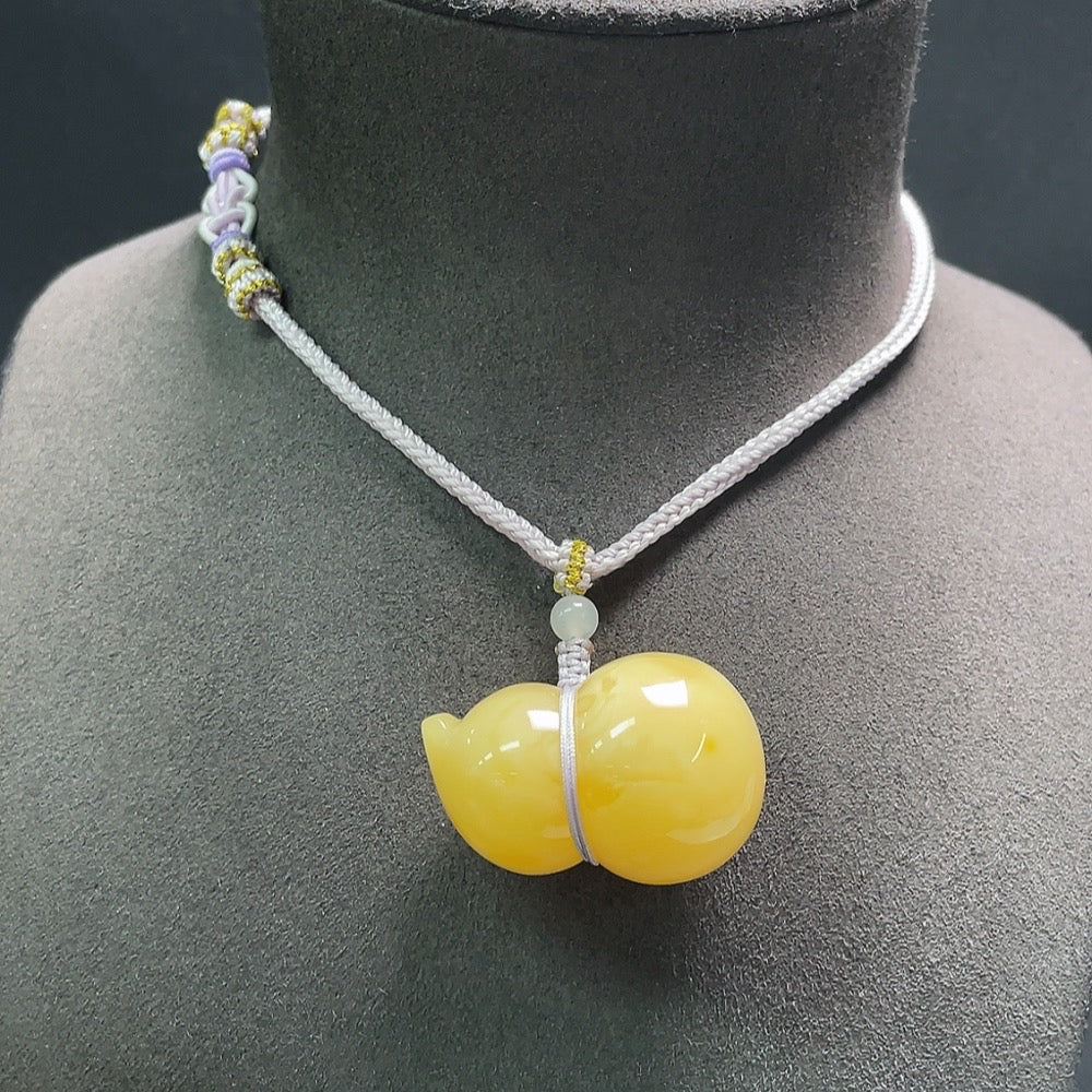 Amber beeswax pendant with Hetian jade and rope from HUILIU HQ, showcasing the natural amber and green jade details.