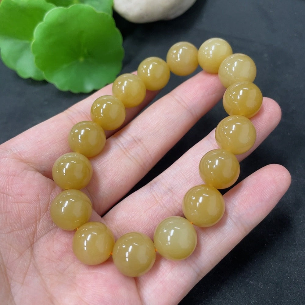 Hetian Jade bracelet by HKHQ with 11.8mm beads, showcasing smooth, polished green jade stones on a delicate bracelet.