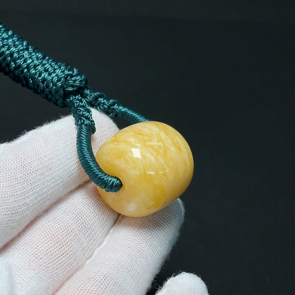 Amber beeswax pendant from HKHQ with a natural amber stone, weight approximately 10.99g, displayed on a cord.