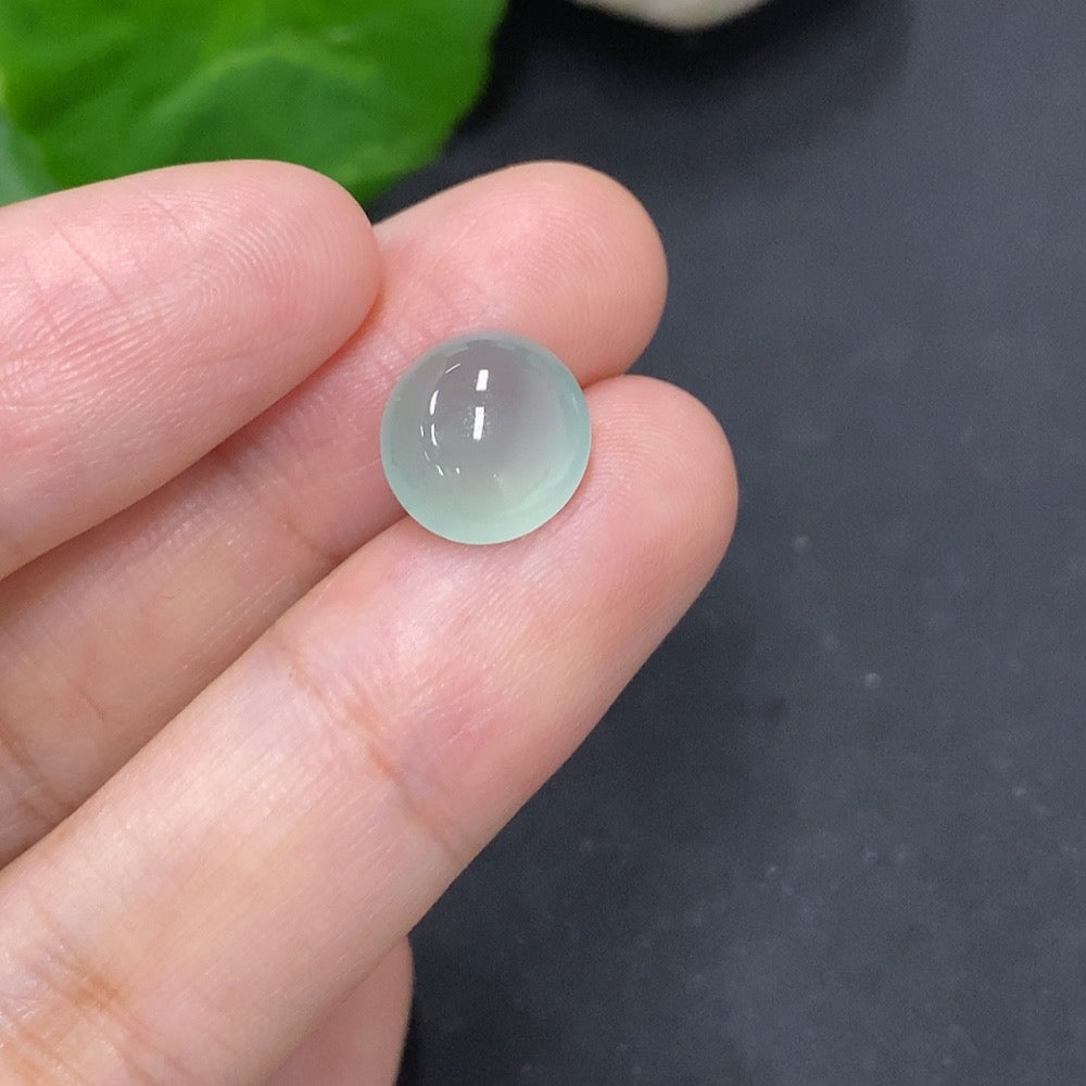 Jadeite cabochon jewelry from HKHQ, polished green gemstone with smooth rounded surface, weighing 0.8 grams.