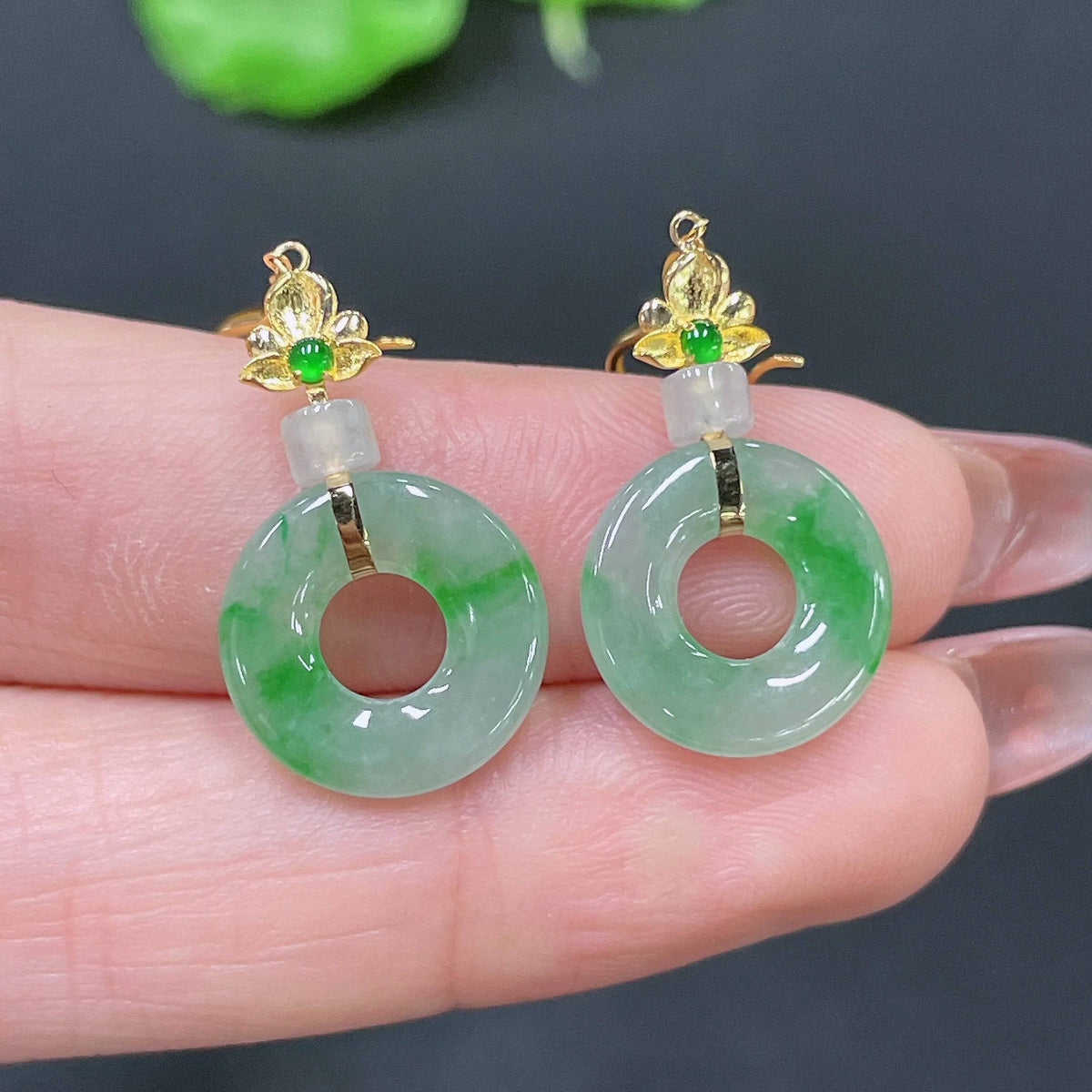 Huiliu Certified Jadeite earrings featuring smooth, polished jade stones in a delicate dangle design on a white background.