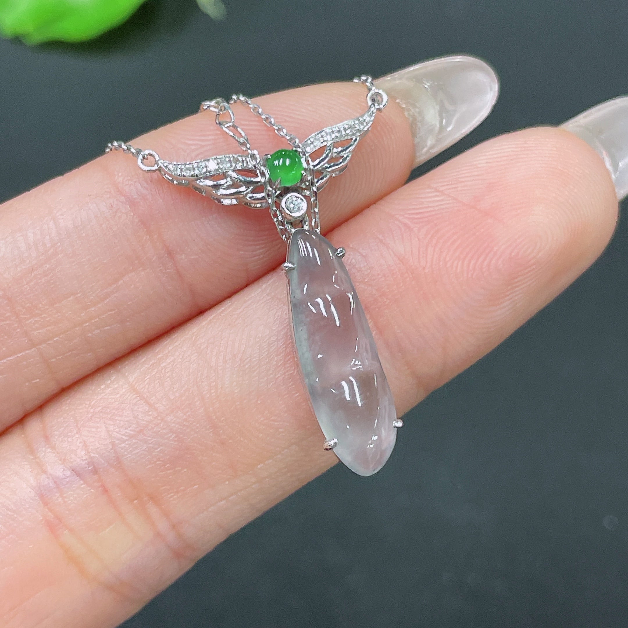 Jadeite bean pendant set in 18k gold with diamond accents, attached to a delicate chain, showcasing elegant jewelry craftsmanship.