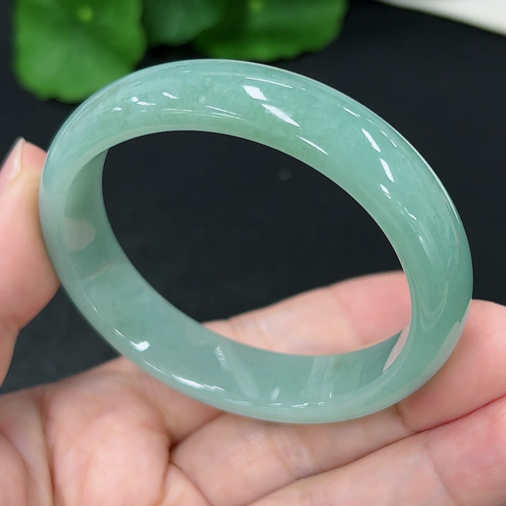HKHQ jadeite oval bangle in size 53.2 with a polished finish, showcasing its smooth, rounded design and vibrant green color.