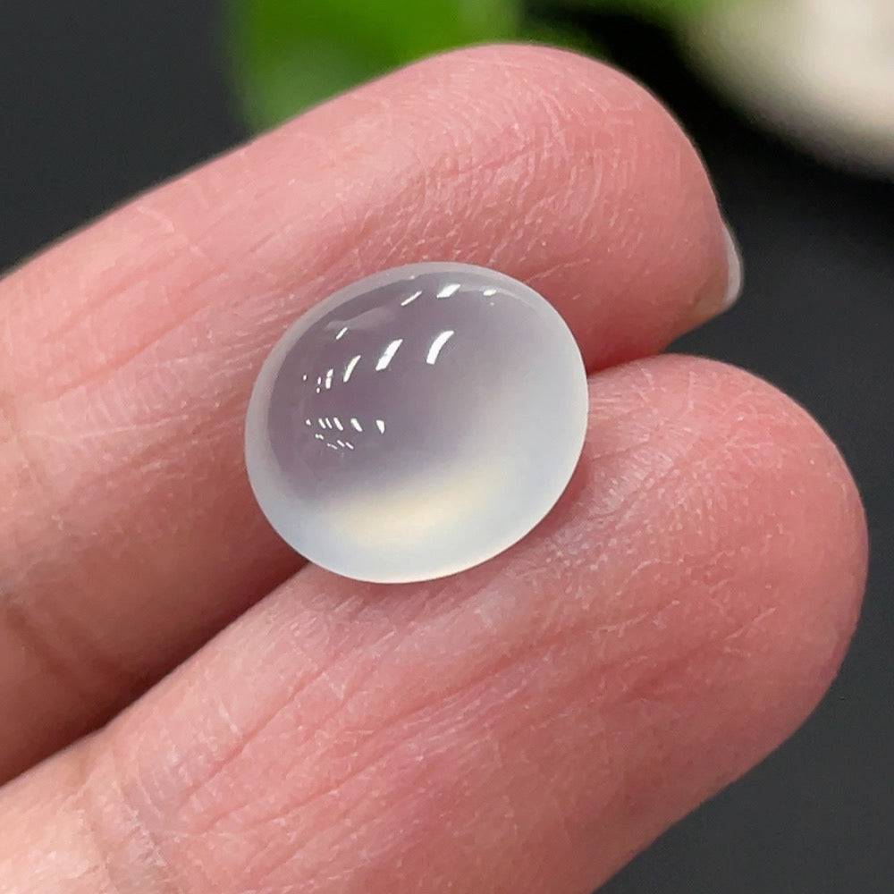 Jadeite cabochon from HUILIU HQ, weighing approximately 0.73g, showcasing smooth, polished green jade with a rounded, glossy surface.