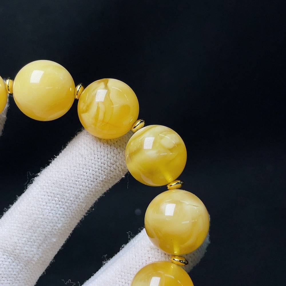 Amber beeswax bracelet with visible repairs, non-metal cord, accented with non-natural stones, size approximately 16.5mm, Huiliu Certified.