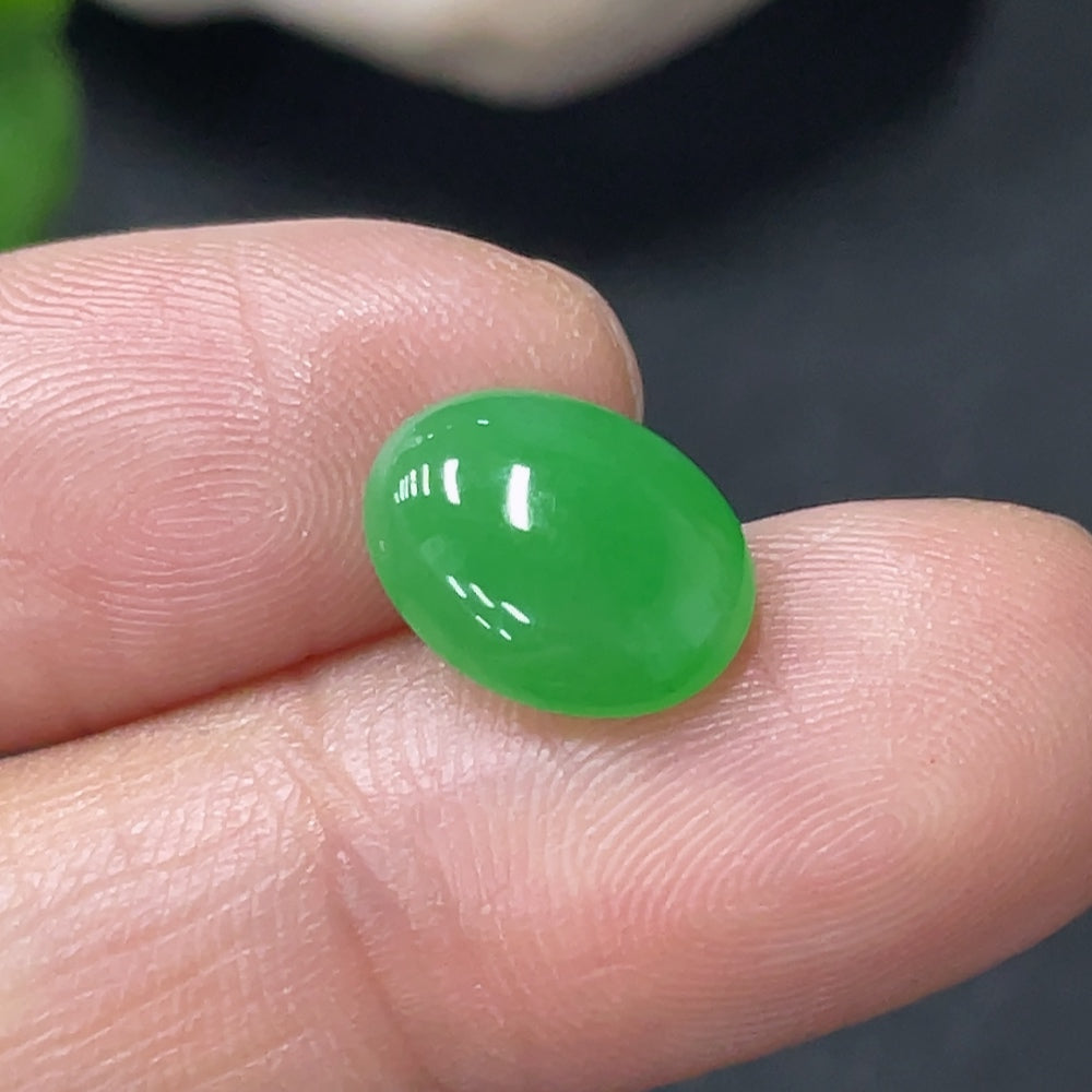 Close-up of a green jadeite cabochon from HUILIU HQ, weighing approximately 0.67g, showcasing smooth, polished surface and vibrant color.