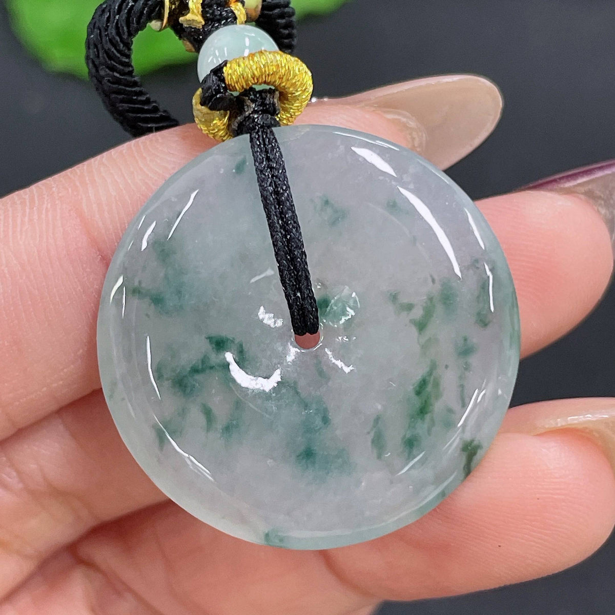 Huiliu Jadeite pendant with peace knot design on cord, showcasing smooth green jade and intricate craftsmanship.