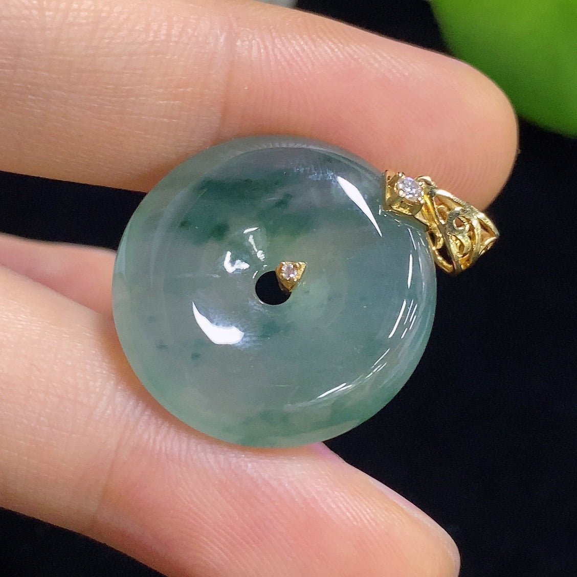 Jadeite peace knot pendant inlaid with diamonds, 18k gold, weighing approximately 5.82g, displayed on a jewelry stand.