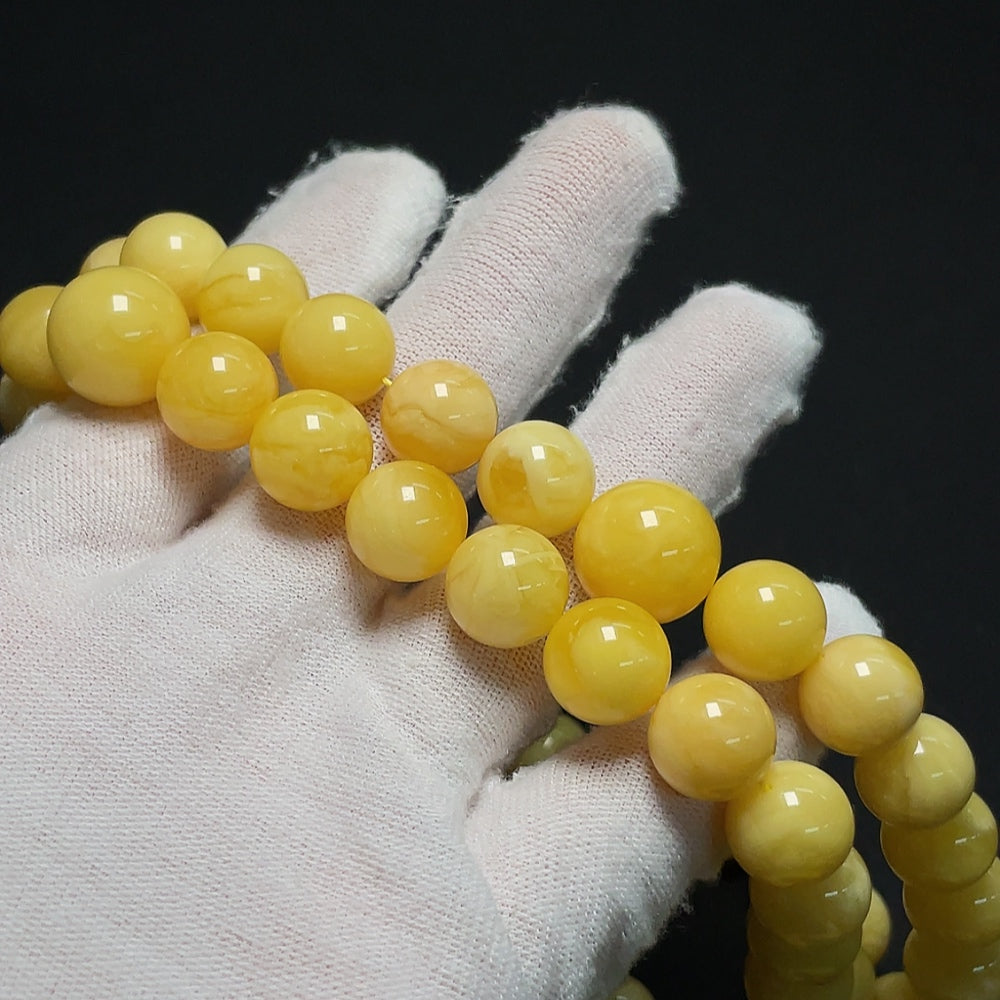 Amber HKHQ beeswax bead strand with visible repairs, 11.4-14mm, weighs approx. 60.86g, natural amber jewelry piece.