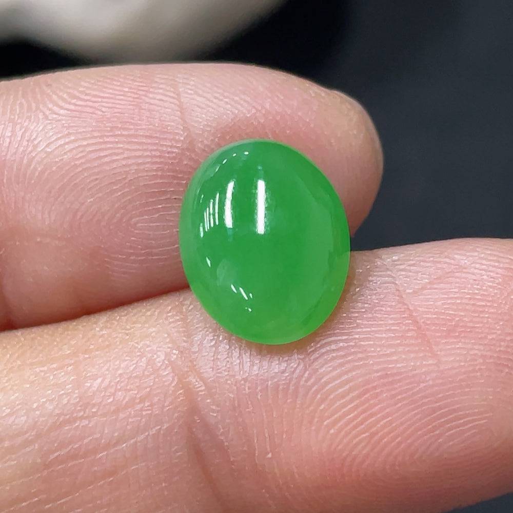 Jadeite cabochon gemstone from HUILIU HQ, smooth oval shape, showcasing vibrant green color and polished surface.