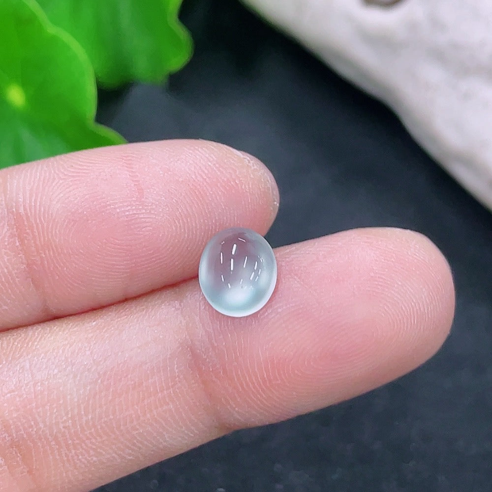 Green jadeite cabochon jewelry piece showing smooth, polished surface with subtle natural color variations and a lightweight appearance.