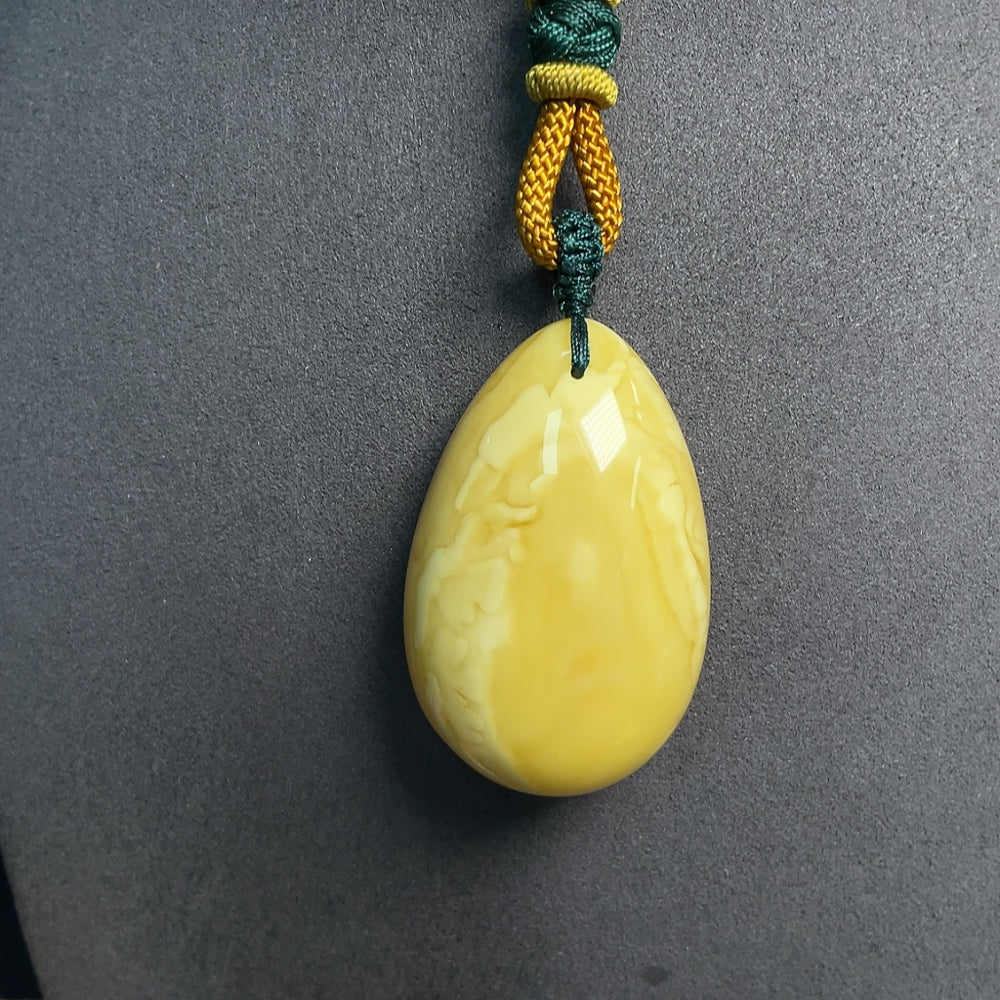 Huiliu certified amber beeswax pendant with attached rope, showcasing warm amber tones and natural handcrafted craftsmanship.