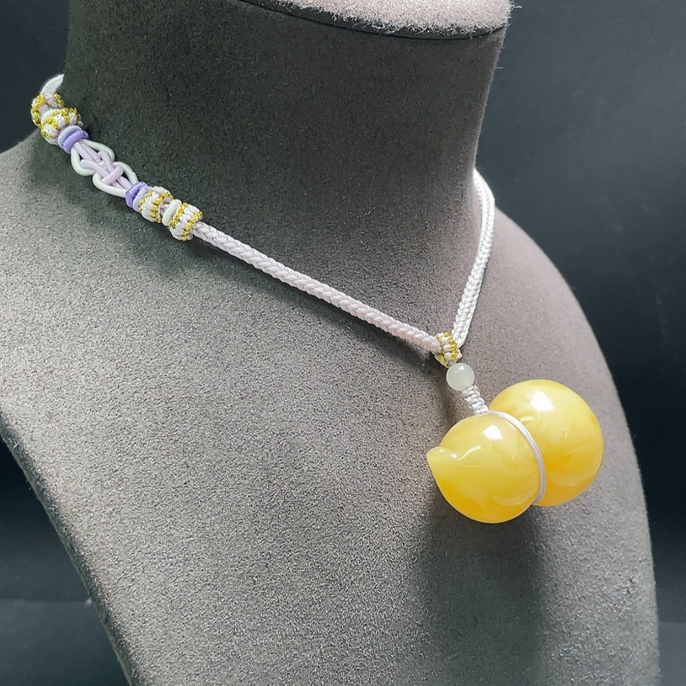 Amber beeswax pendant with Hetian jade and rope from HUILIU HQ, showcasing a natural, polished jewelry piece.