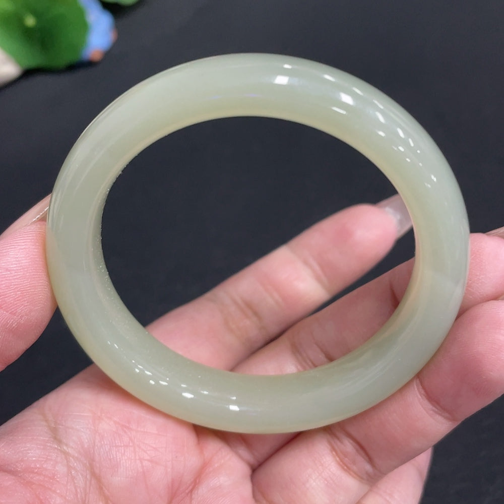 Huiliu certified Hetian jade round bangle with smooth polished surface and natural greenish hue, traditional jewelry piece.