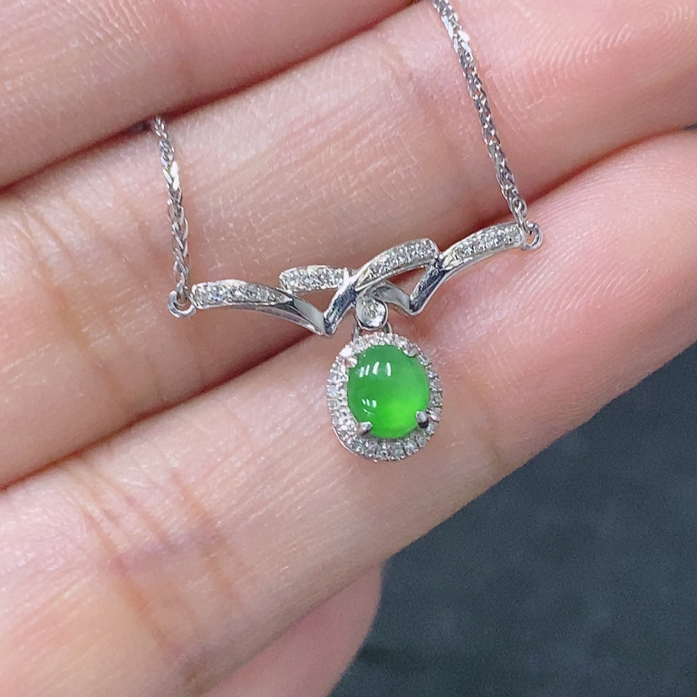 Jadeite cabochon pendant with 18K gold setting and diamond accents, featuring polished green jade and intricate gold detailing.
