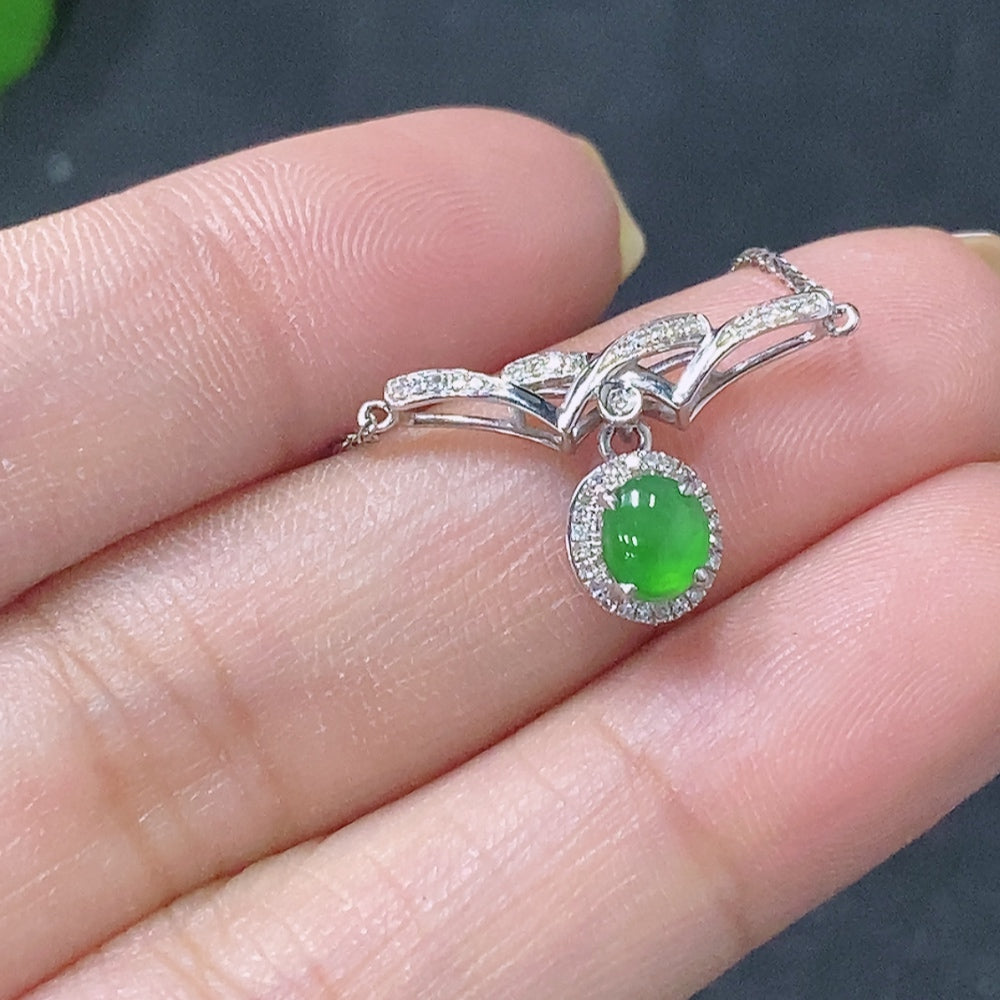 Jadeite cabochon pendant with 18K gold setting and diamond accents, featuring smooth green jade gemstone.