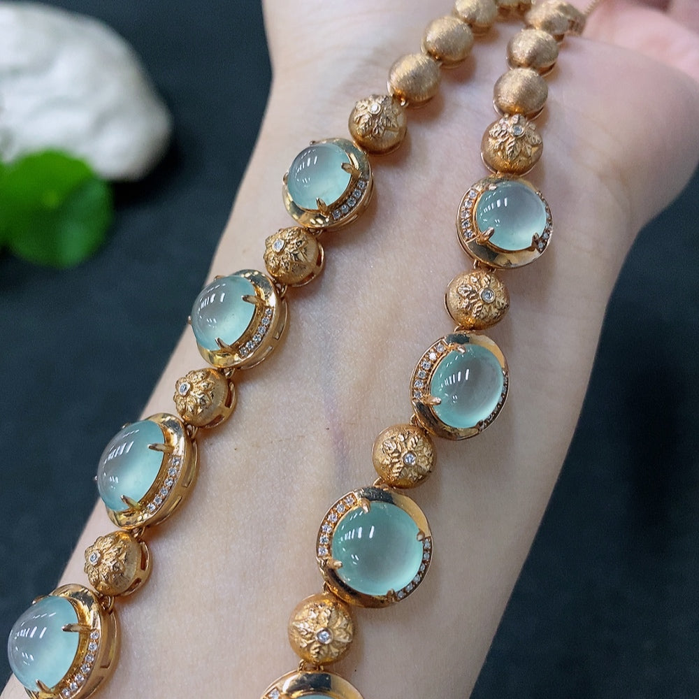 Jadeite cabochon necklace with 18K gold and diamond accents, featuring a green jade pendant on a gold chain.