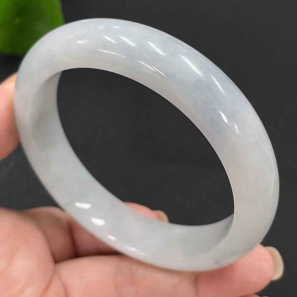 Huiliu HQ jadeite round bangle with smooth, polished surface, showcasing vibrant green jadeite in a natural light setting.