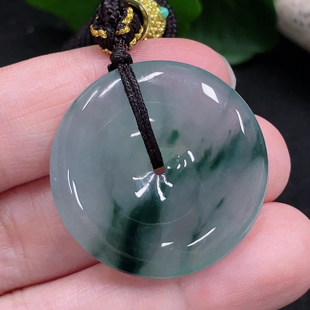 HUILIU HQ jadeite Peace buckle pendant featuring a polished jadeite stone with intricate carved design on a cord.