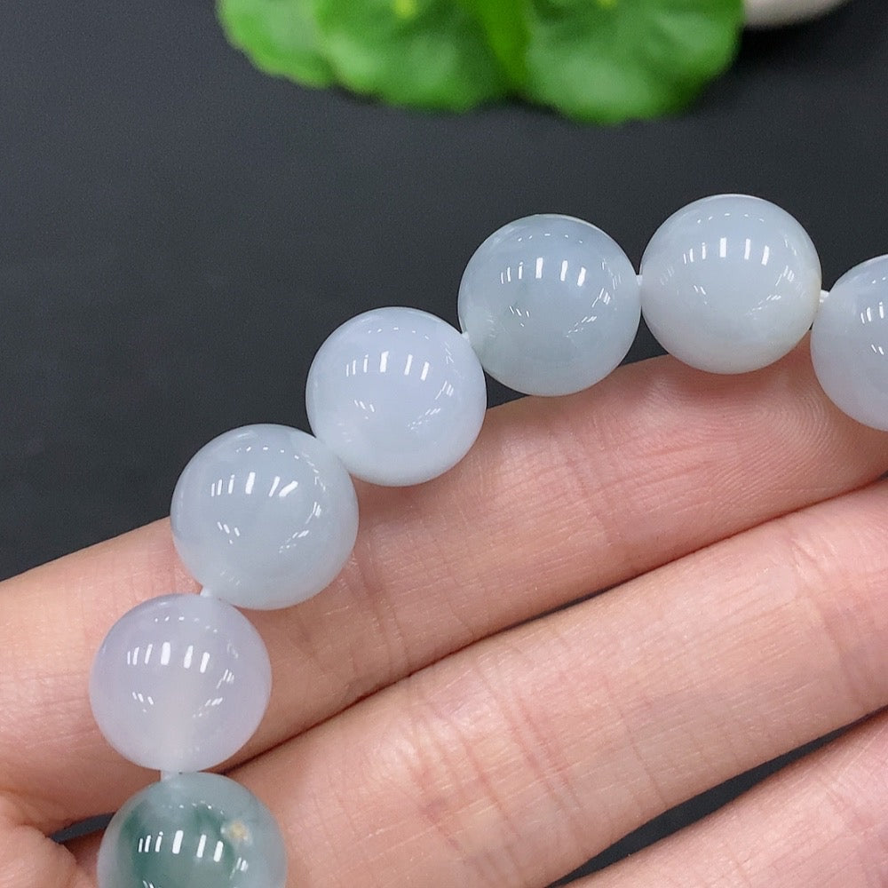 Huiliu Natural Grade A Jadeite bead bracelet with 12.2mm beads, showcasing smooth, polished jade stones on a clear string.