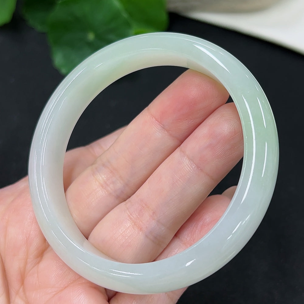 HKHQ Jadeite round bangle, size 56 with a polished finish, showcasing its vibrant green color and smooth, rounded design.