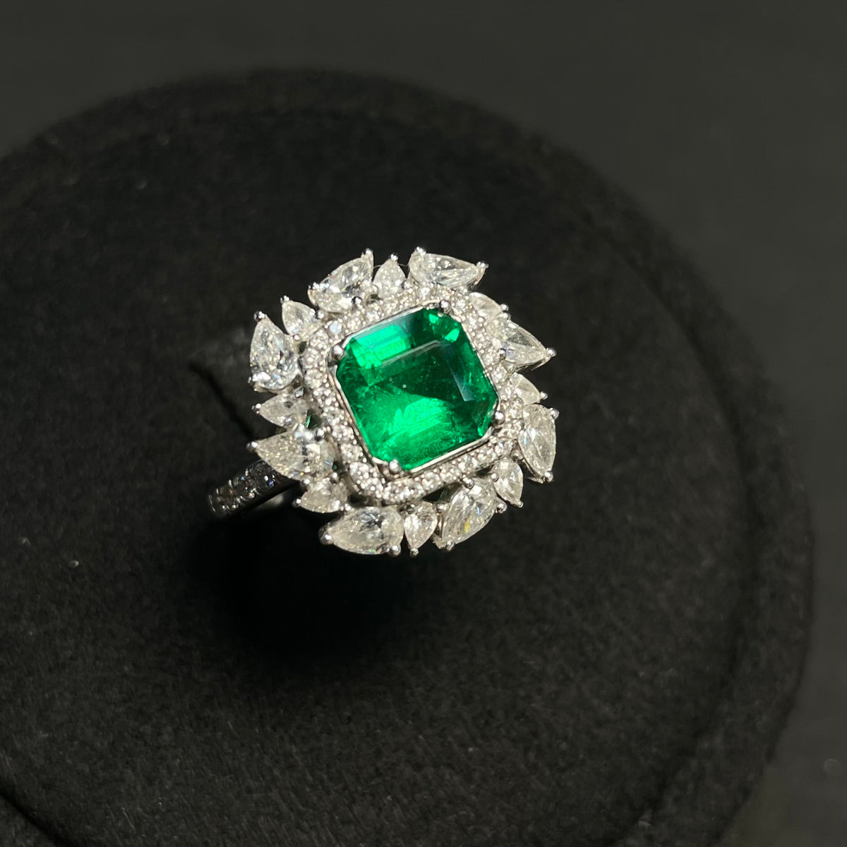 Emerald ring with diamond accents in 18K gold, featuring enhanced clarity, showcased on a neutral background.