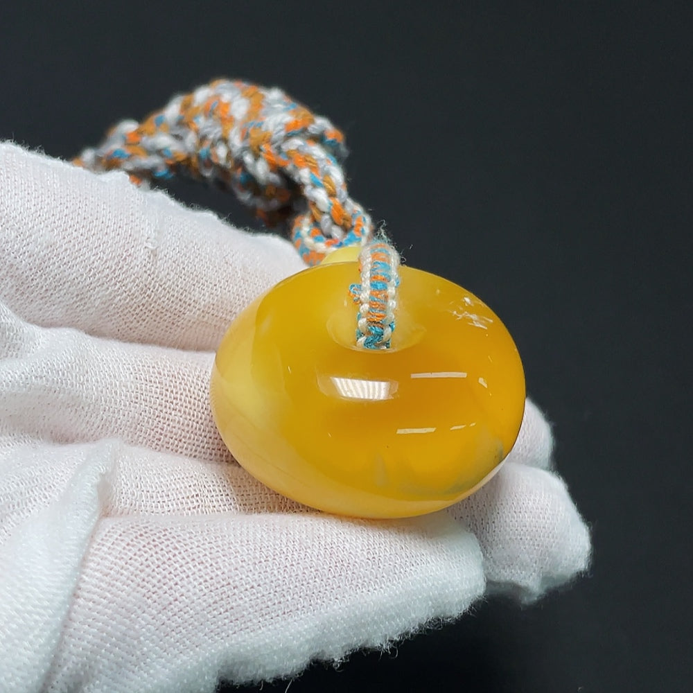 Amber beeswax pendant with cord from HKHQ, showcasing warm amber tones and handcrafted design.