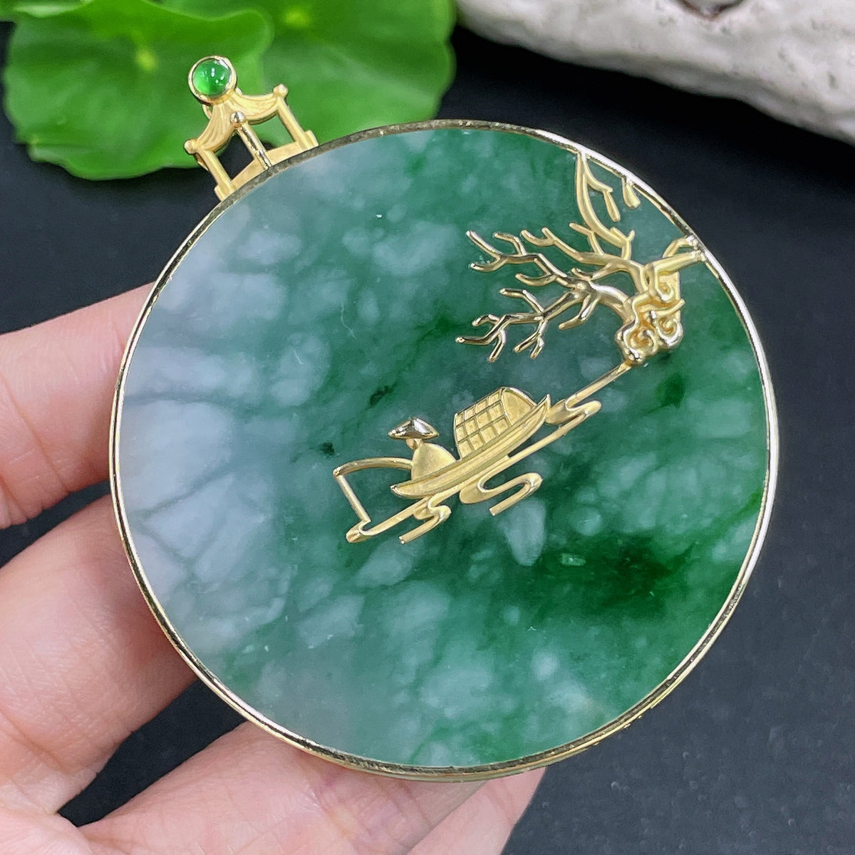 Jadeite pendant with 18k gold inlay, crafted with adhesive, featuring a smooth, polished jade stone on a jewelry display.