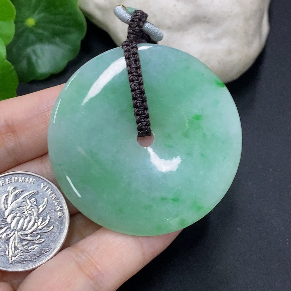 Jadeite pendant with peace knot design on cord, weighing 28.34g, showcasing smooth green jade with intricate knot detail.