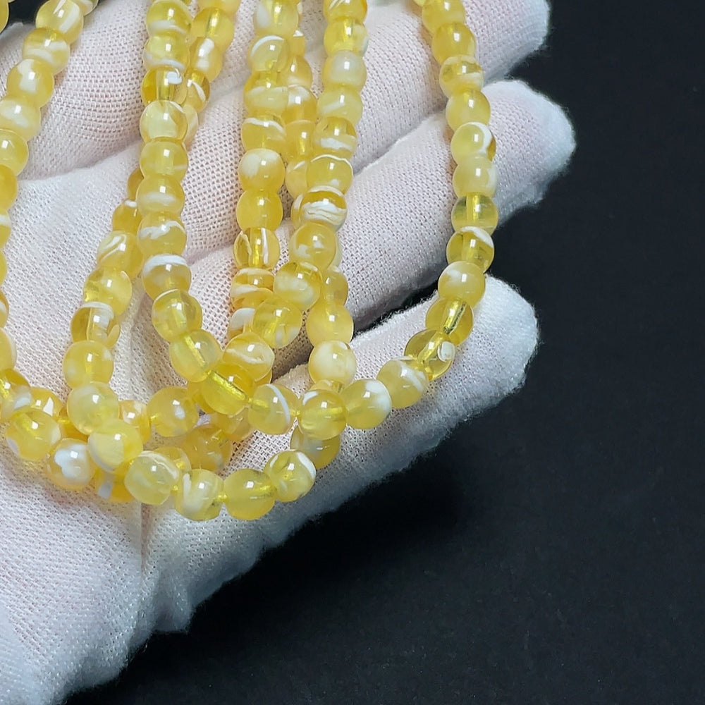 Amber HKHQ beeswax bead strand with approx. 5.5mm beads and non-natural accent stones, weighing about 14.32g, shown in the image.