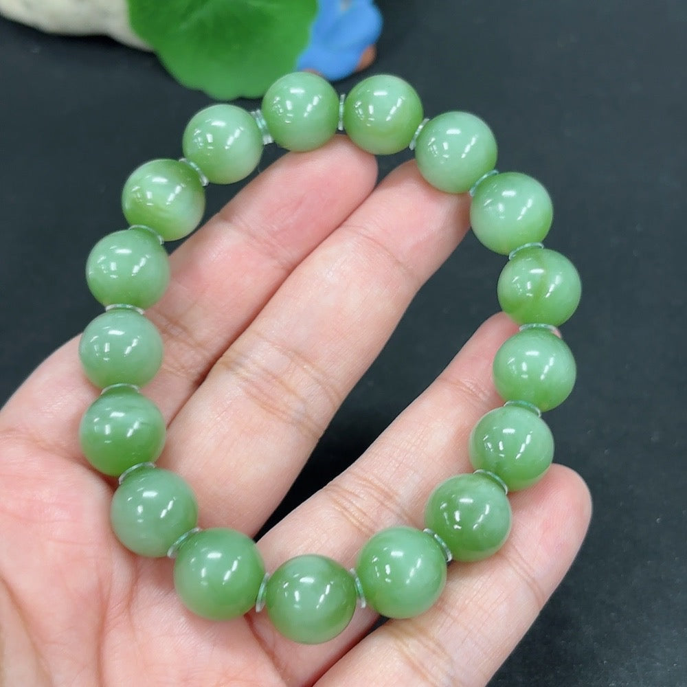 Green Hetian Jade bracelet featuring smooth, polished beads from HKHQ, displayed on a neutral background.